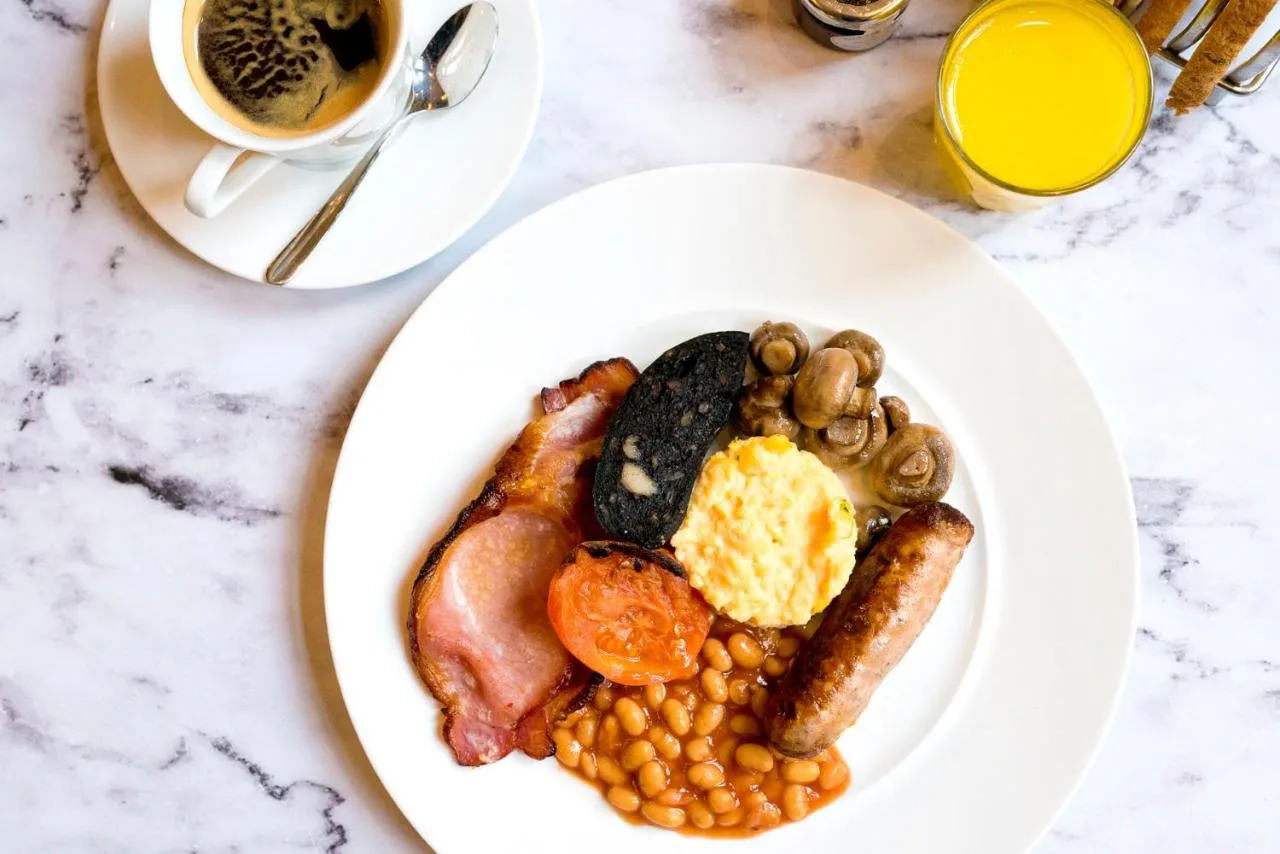 a plate of breakfast food with beans and a cup of coffee at voco St. David's Cardiff by IHG in Cardiff