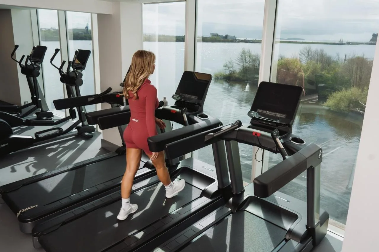 a woman walking on a treadmill in a gym at voco St. David's Cardiff by IHG in Cardiff
